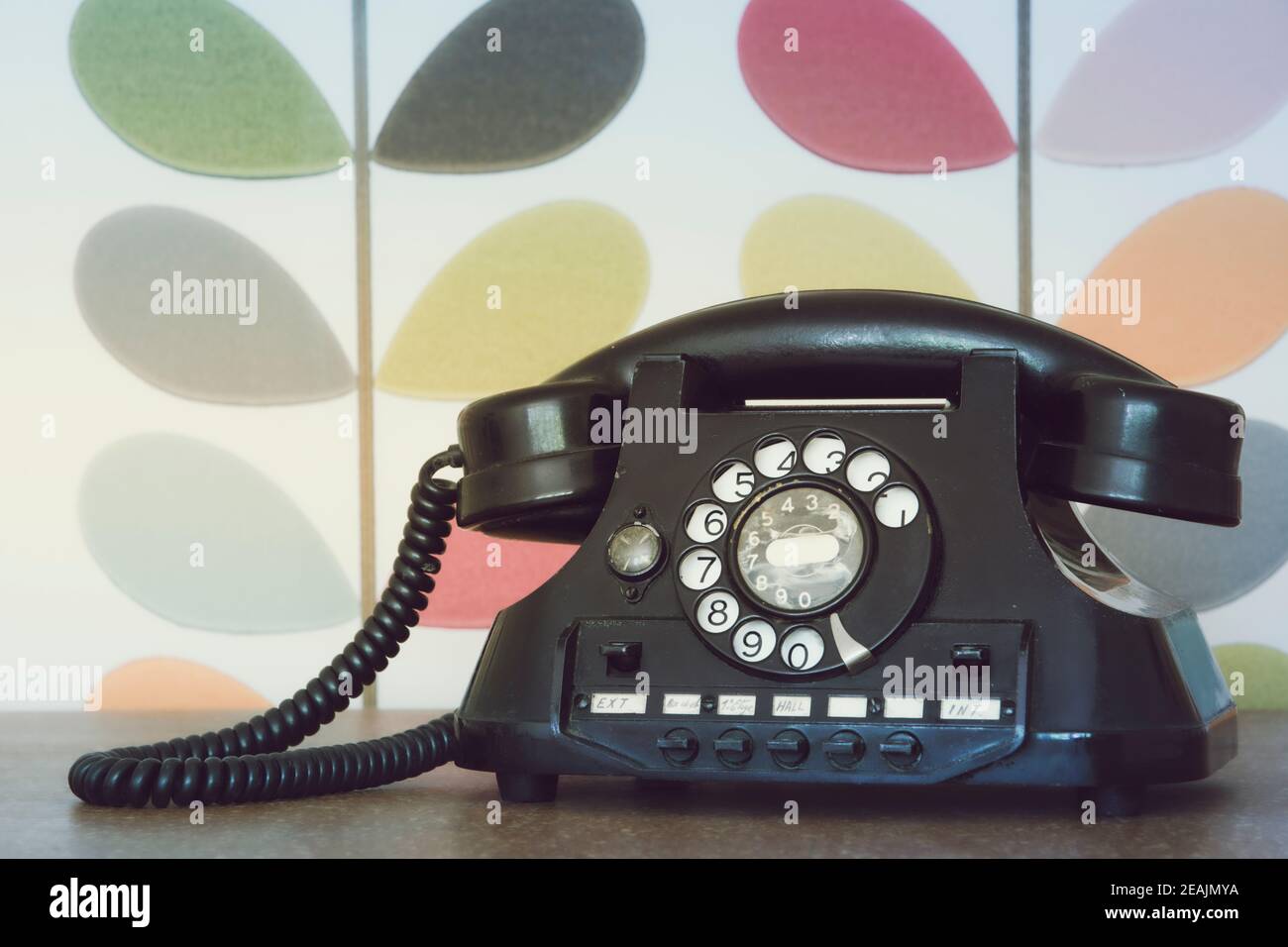 Vecchio telefono retro e vintage contro carta da parati colorata Foto Stock