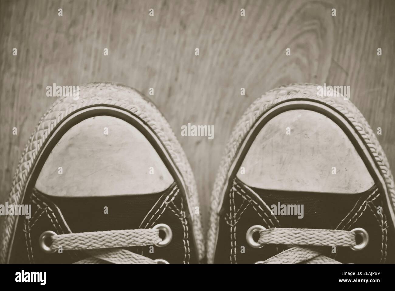 orn out converse Chuck Taylor punte per sneakers All-Star, con tessuto nero, su pavimento in legno. Modifica creativa. Foto Stock