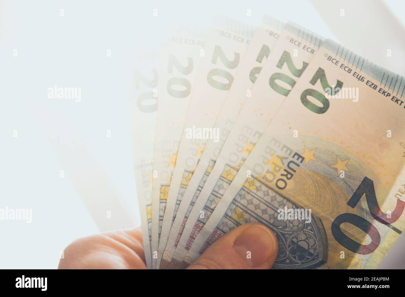 La tenuta a mano ha sparso 20 banconote in euro contro la luce solare forte Foto Stock