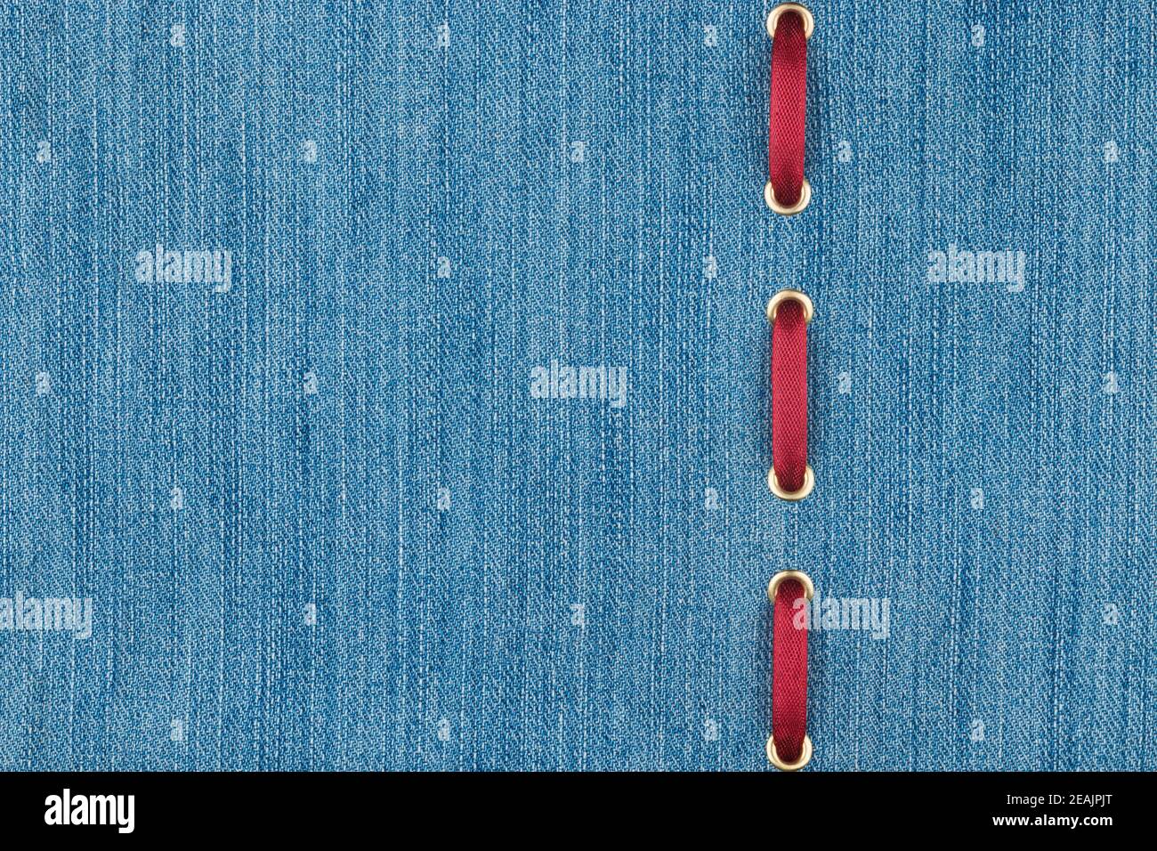 Il nastro di seta rossa è inserito in un tessuto in denim leggero. Con luogo per il testo. Foto Stock