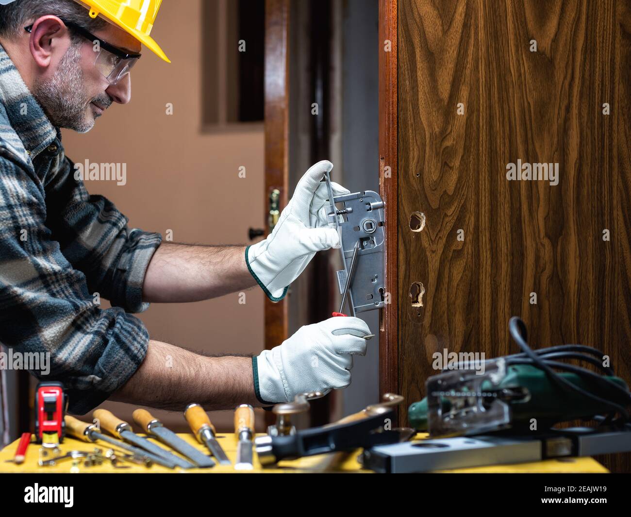 Falegname al lavoro ripara e installa la serratura della porta. Carpenteria. Foto Stock