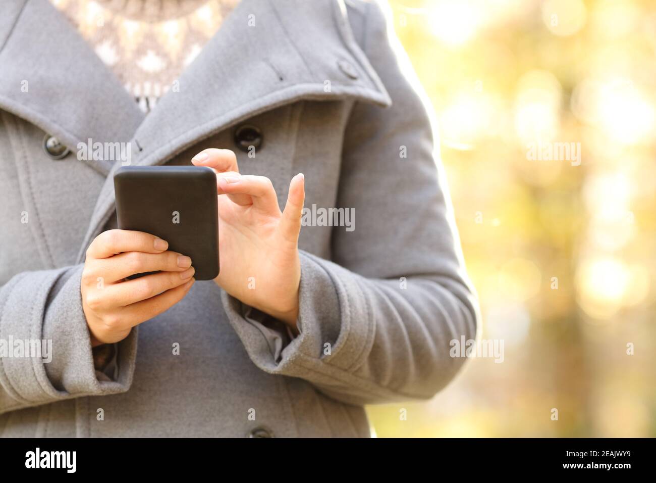 La donna passa a mani con uno smartphone in autunno o in inverno Foto Stock