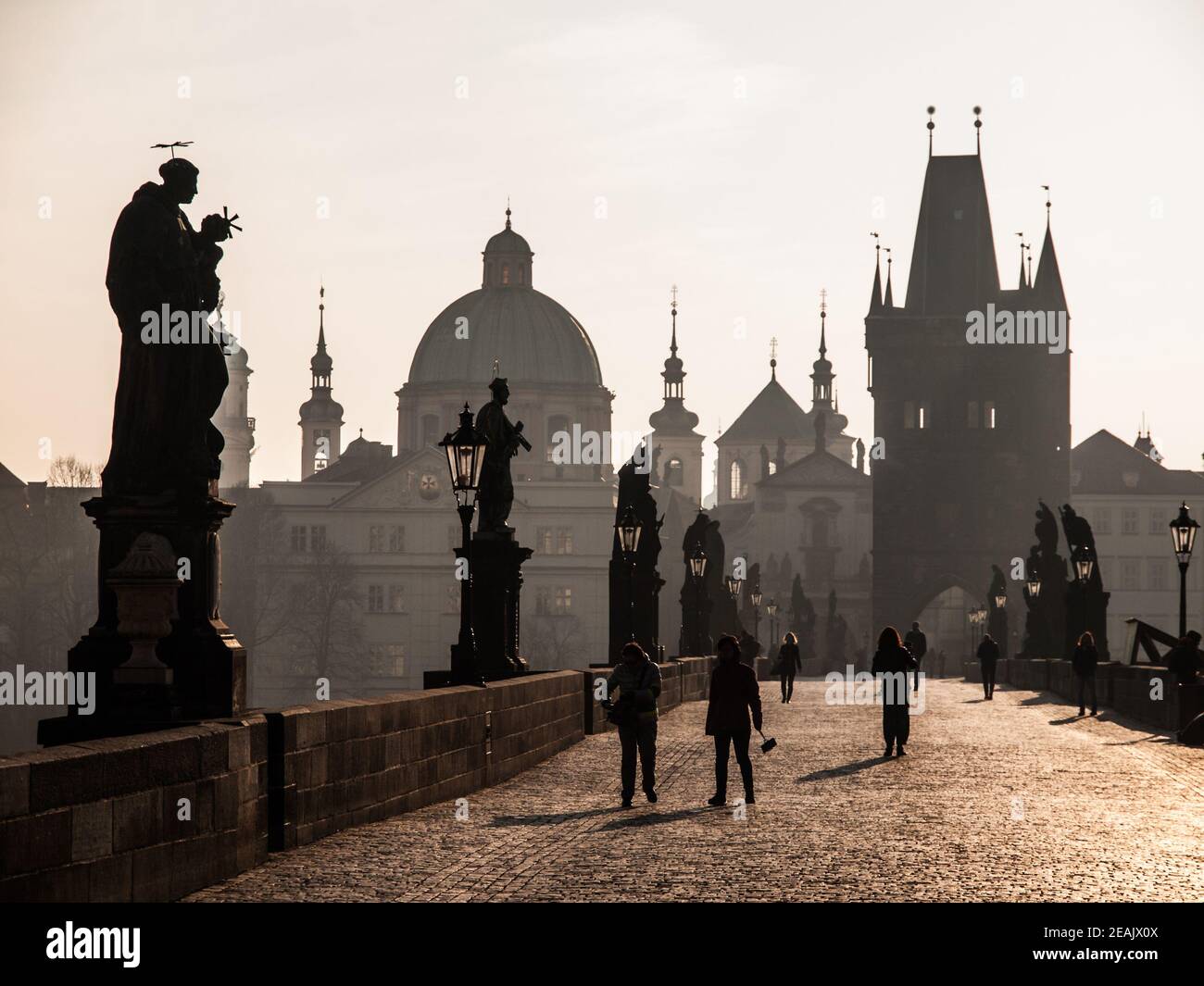 I turisti camminano sul Ponte Carlo la mattina soleggiata sotto le sagome delle statue e delle torri della Città Vecchia, Praga, Repubblica Ceca Foto Stock