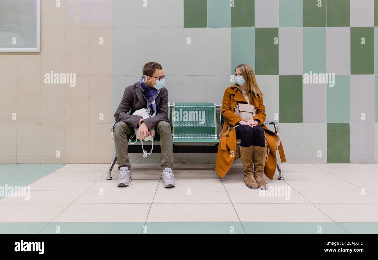 Persone con maschera in attesa di un treno in metropolitana stazione Foto Stock