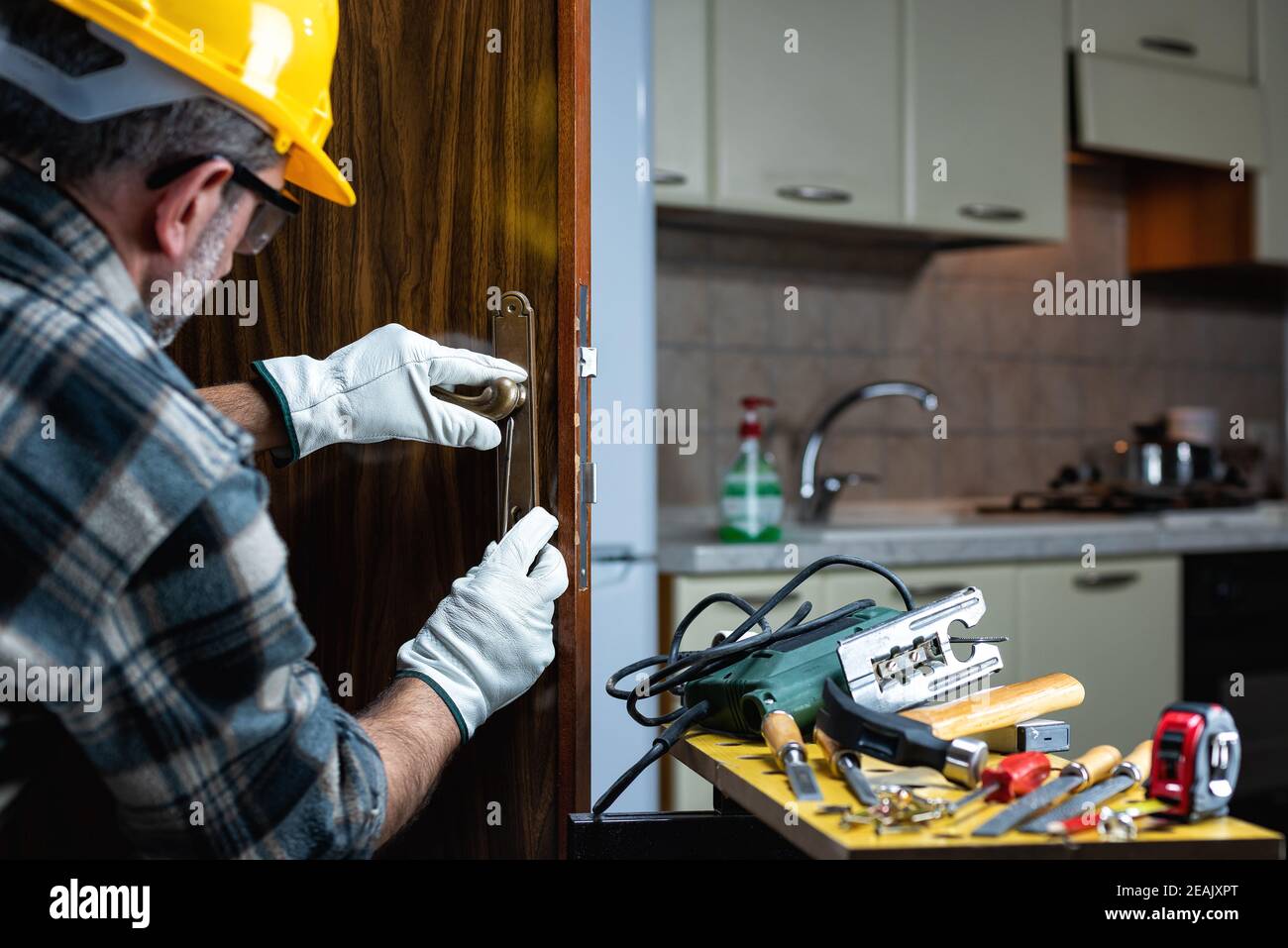 Falegname al lavoro ripara e installa la serratura della porta. Carpenteria. Foto Stock