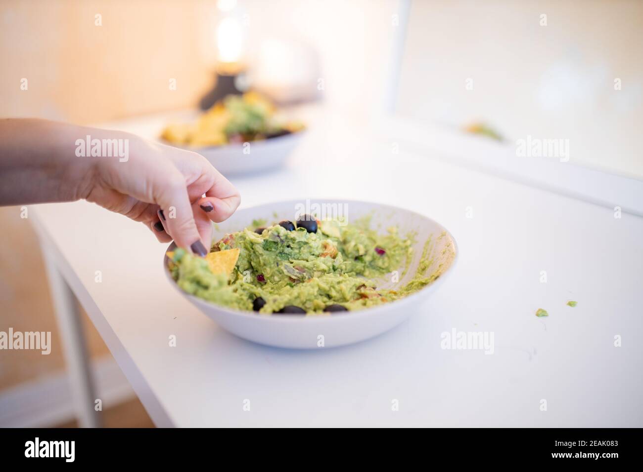 Nachos a mano femminile in salsa di guacamole con olive Foto Stock