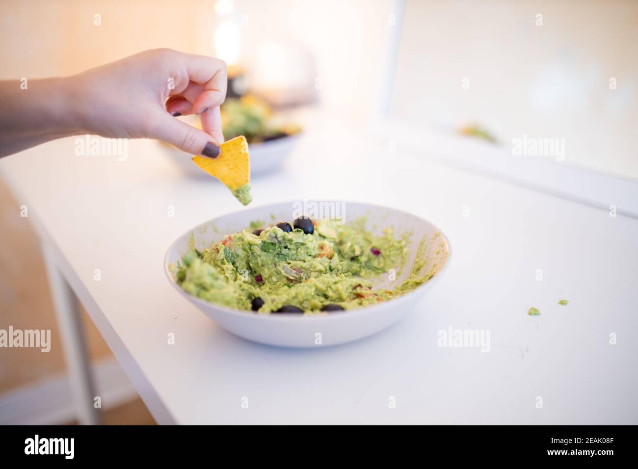 Nachos a mano femminile in salsa di guacamole con olive Foto Stock