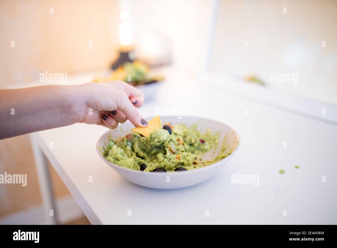 Nachos a mano femminile in salsa di guacamole con olive Foto Stock