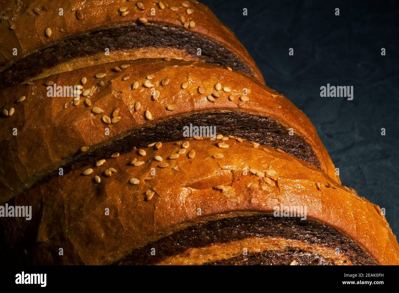 Insolito pane fresco a due colori su sfondo nero, foto in un tasto basso in luce dura, primo piano Foto Stock