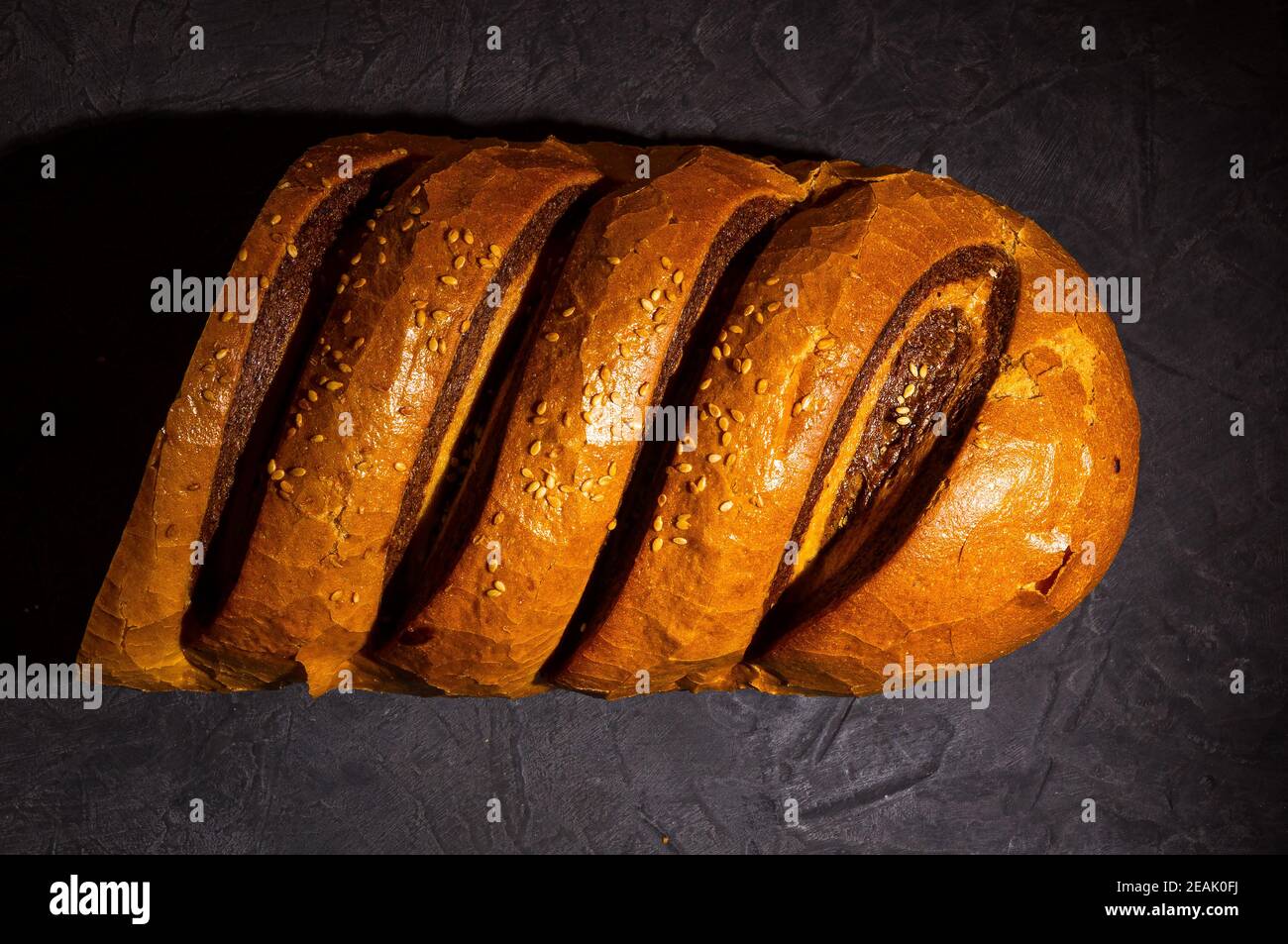 Insolito pane fresco a due colori su sfondo nero, foto in un tasto basso in luce dura, primo piano Foto Stock