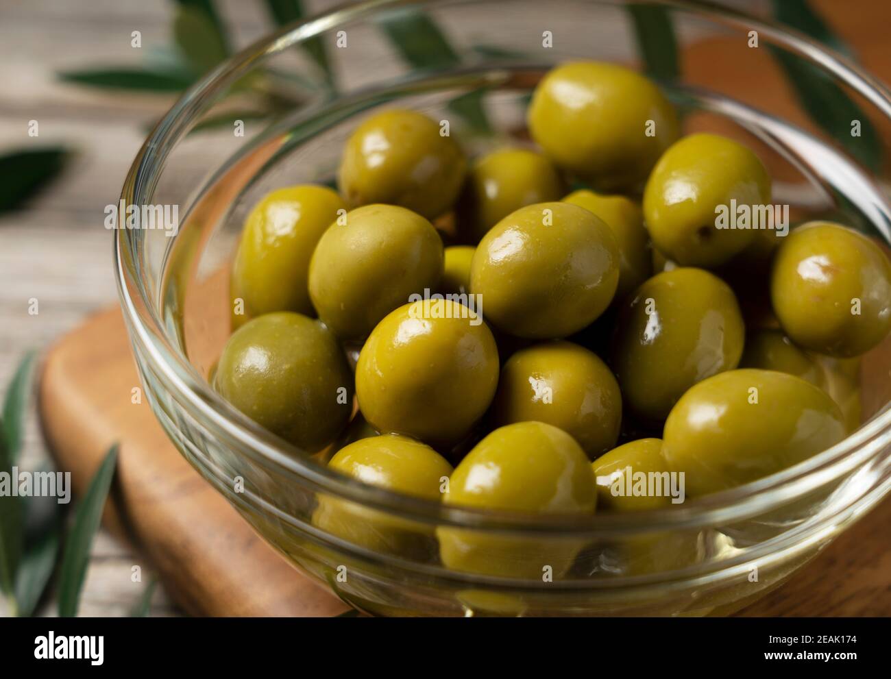 Rami di olive con olive salate poste su uno sfondo di vecchie tavole di legno Foto Stock