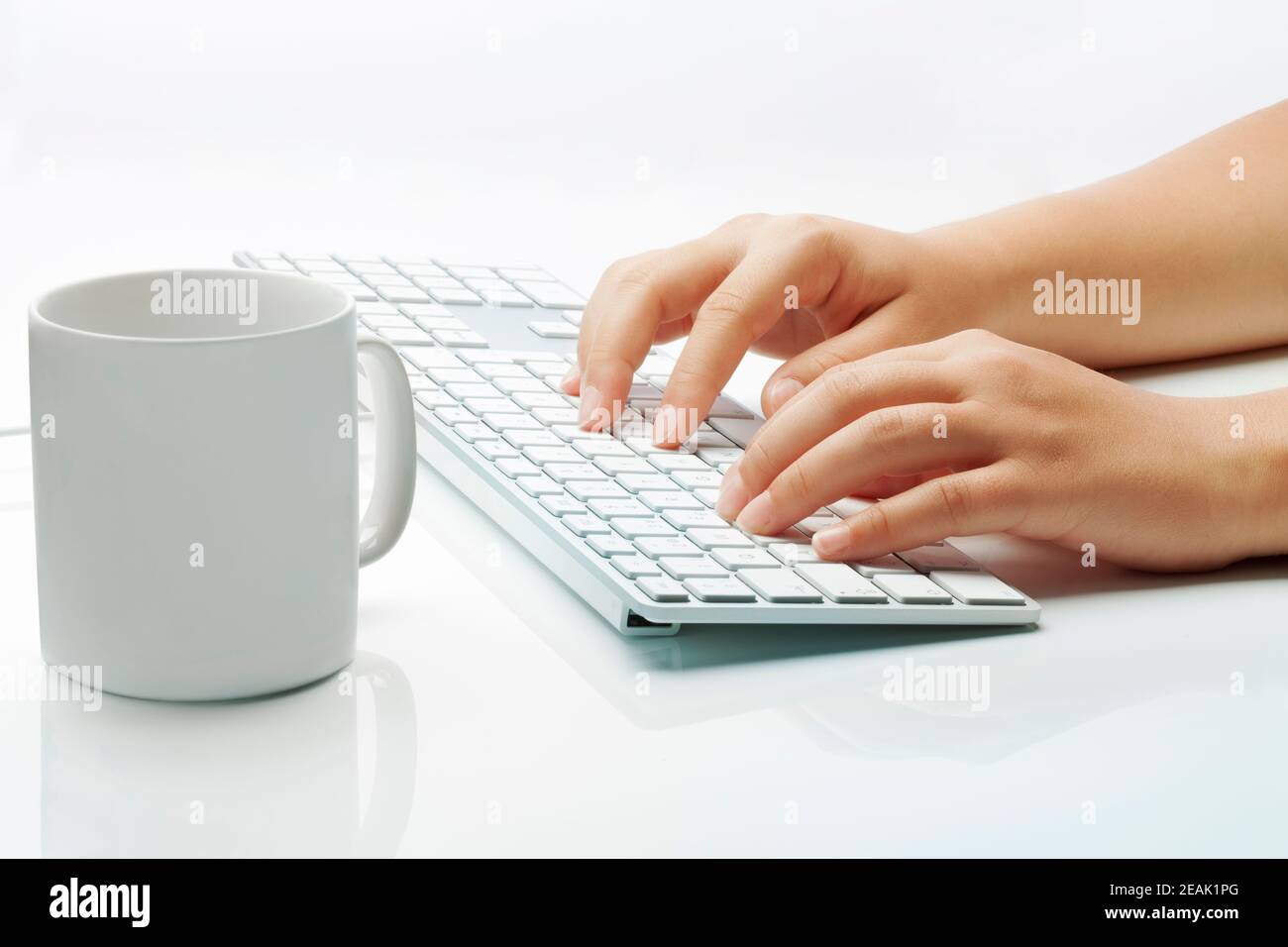 Mani che digitano una tastiera per computer e una tazza di caffè Foto Stock