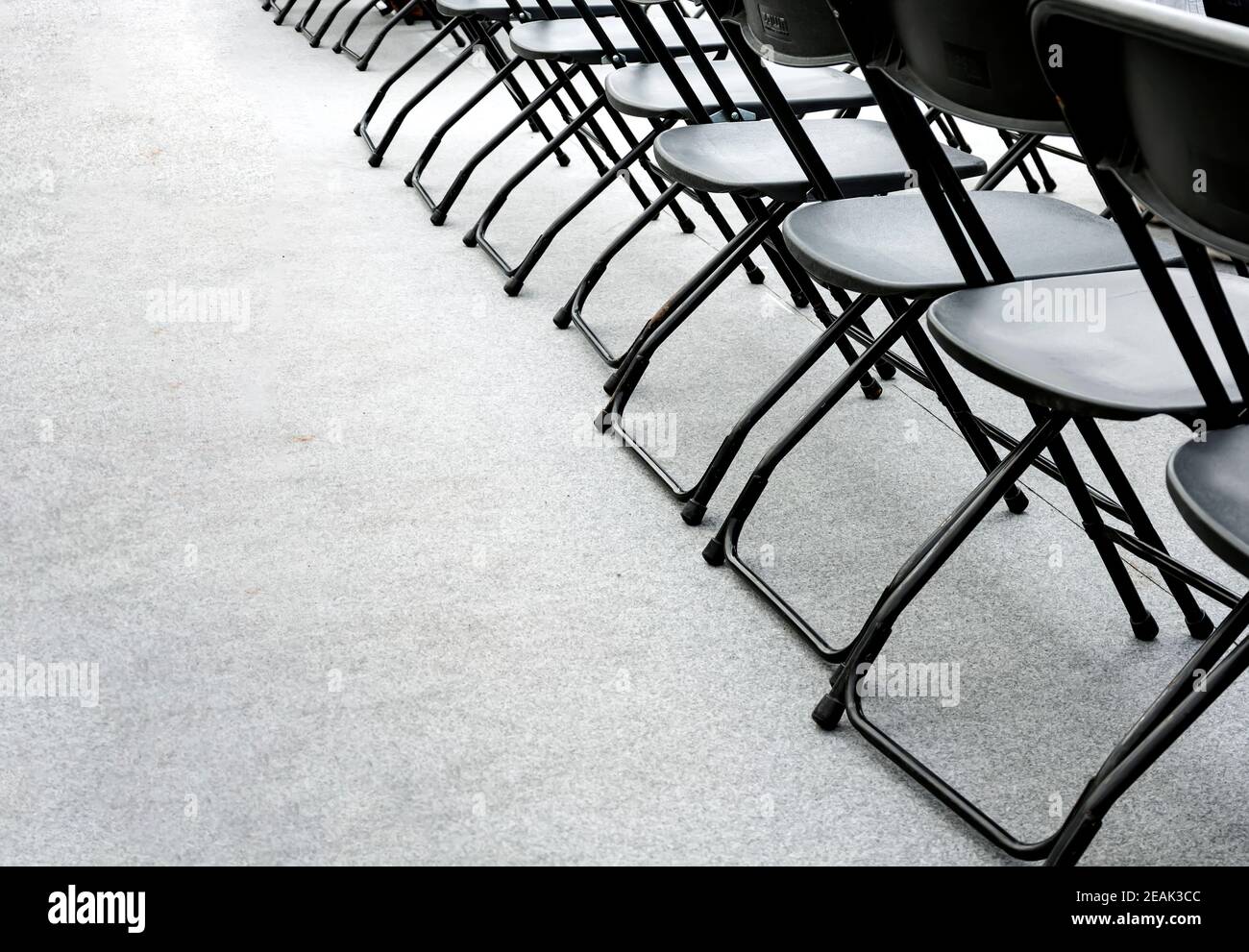 un gruppo di sedie pieghevoli vuote disposte in fila in una sala conferenze. Foto Stock