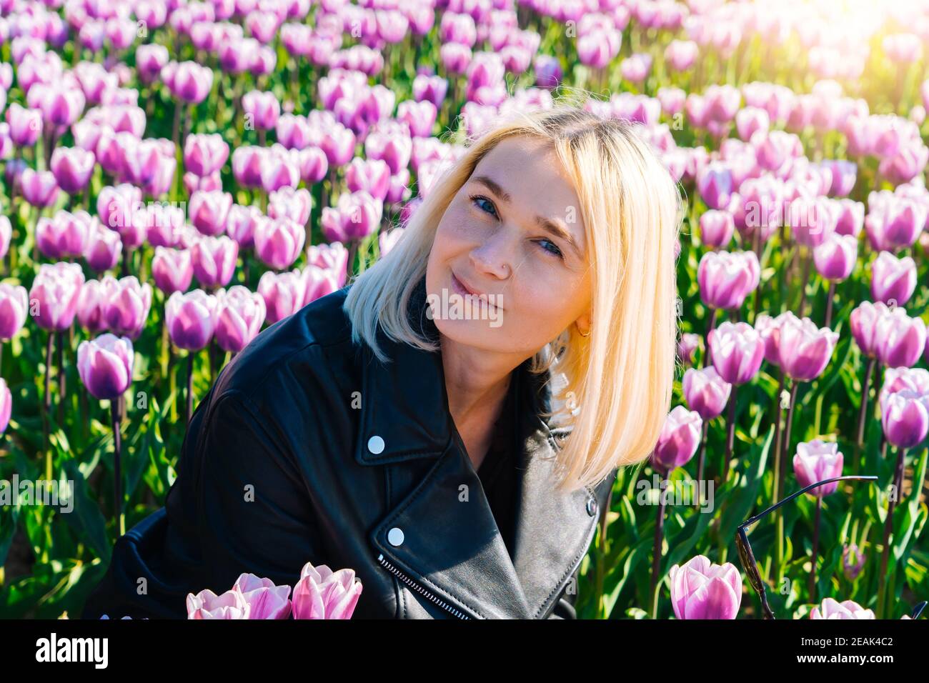 Bella Donna con capelli biondi in piedi in colorati campi di fiori di tulipano nella regione di Amsterdam, Olanda, Paesi Bassi. Magico paesaggio olandese con campo di tulipani in Holland Trevel e concetto di primavera. Foto Stock