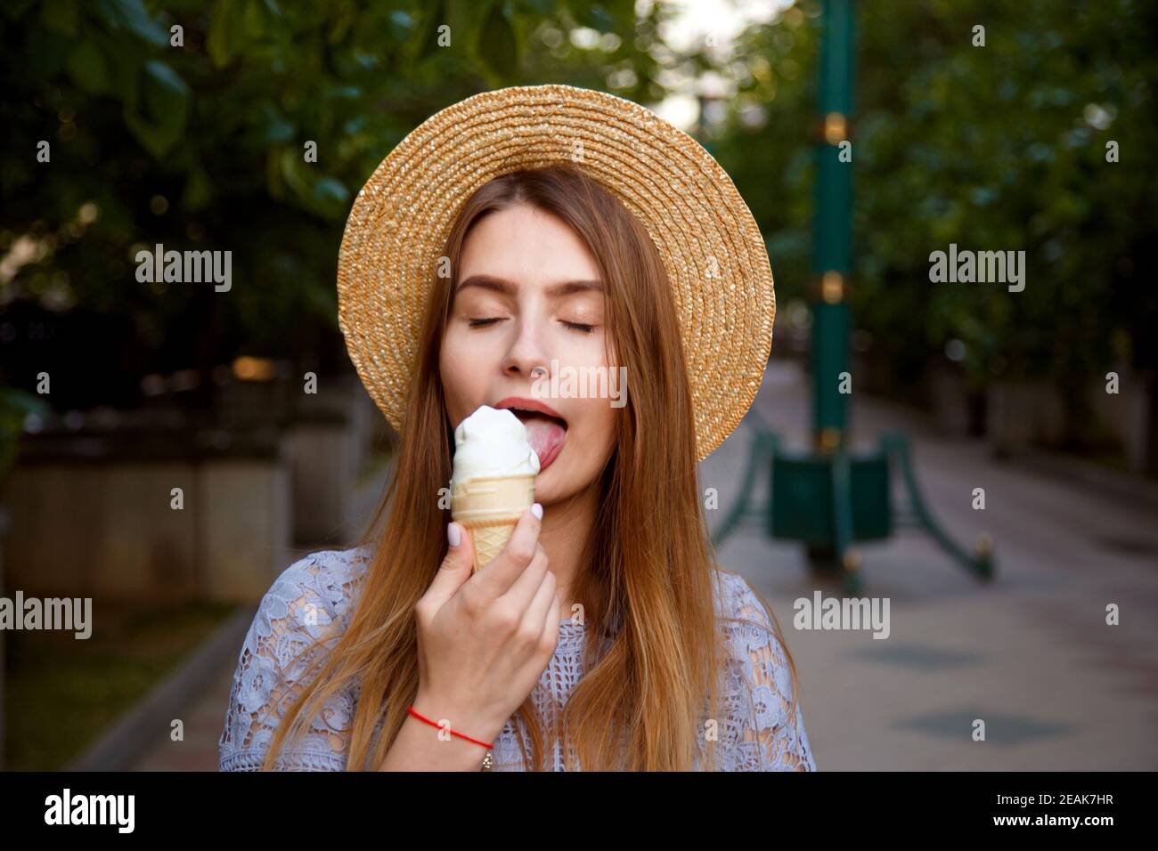 Ragazza in cappello che gode di gelato all'aperto in estate. Foto Stock