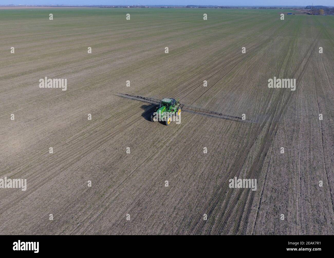 Trattore con sistema incernierato di irrorazione di pesticidi. Concimazione con un trattore, sotto forma di aerosol, sul campo del grano invernale. Foto Stock