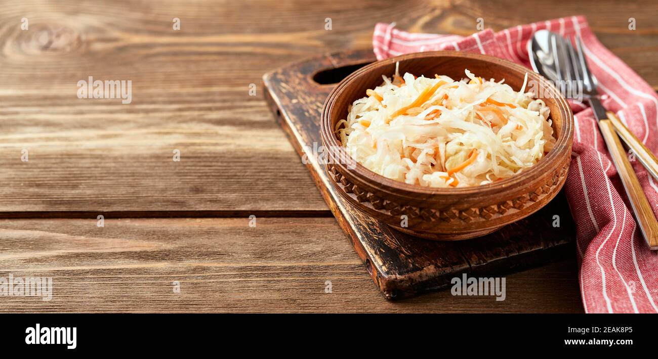 Crauti, cavolo fermentato con carote in ciotola su fondo ligneo con spazio copia. Supercals per sostenere il sistema immunitario. Foto Stock