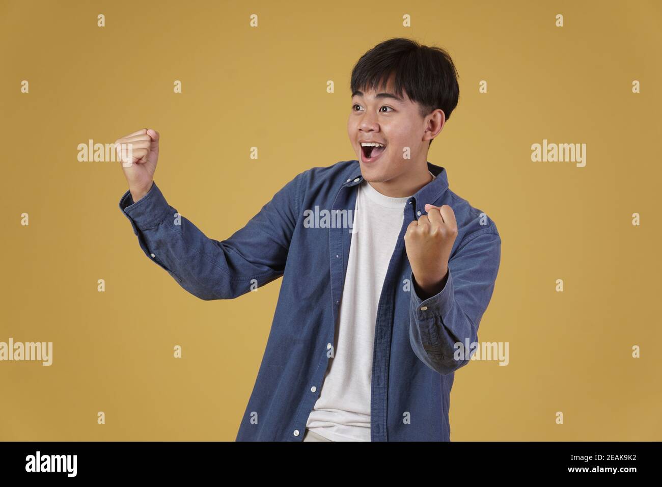 ritratto di felice allegro felice gioia eccitato sopravorato giovane asiatico uomo vestito casualmente isolato su sfondo giallo studio Foto Stock
