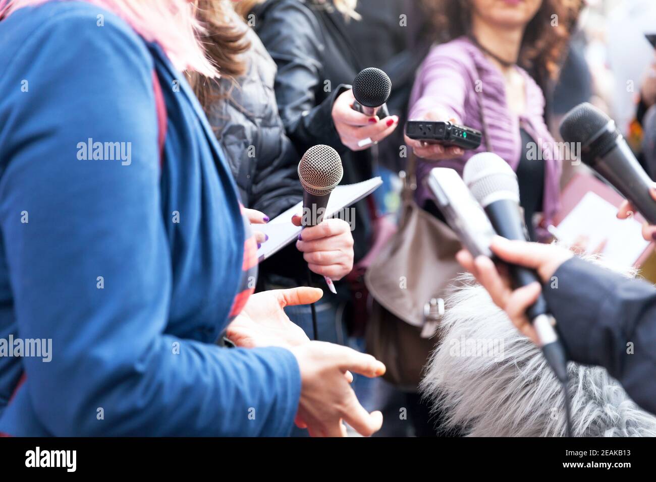 Figura pubblica che parla con i media, giornalisti che tengono microfoni alla conferenza stampa Foto Stock