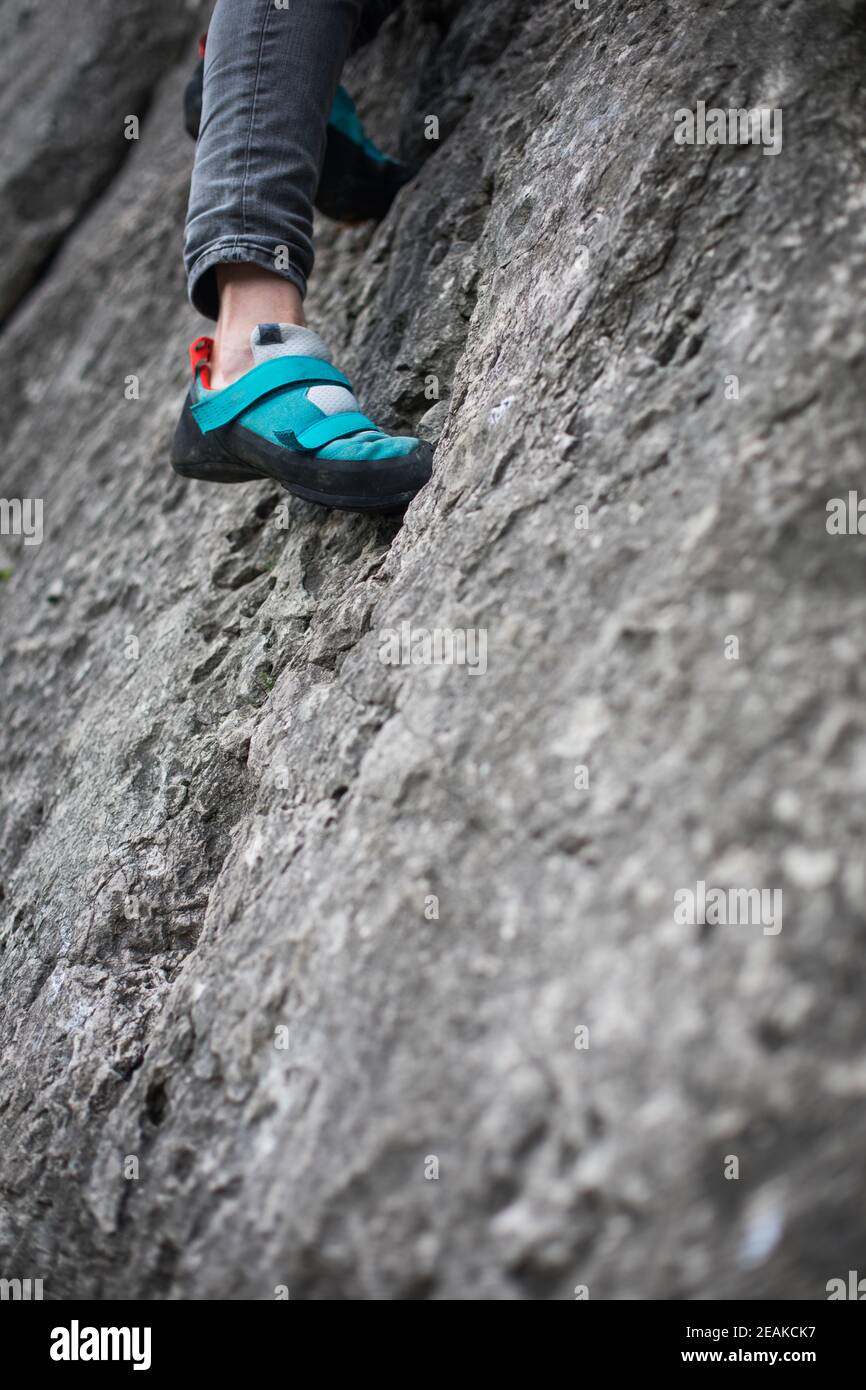 Persona che arrampica mentre indossa le scarpe da arrampicata Foto Stock