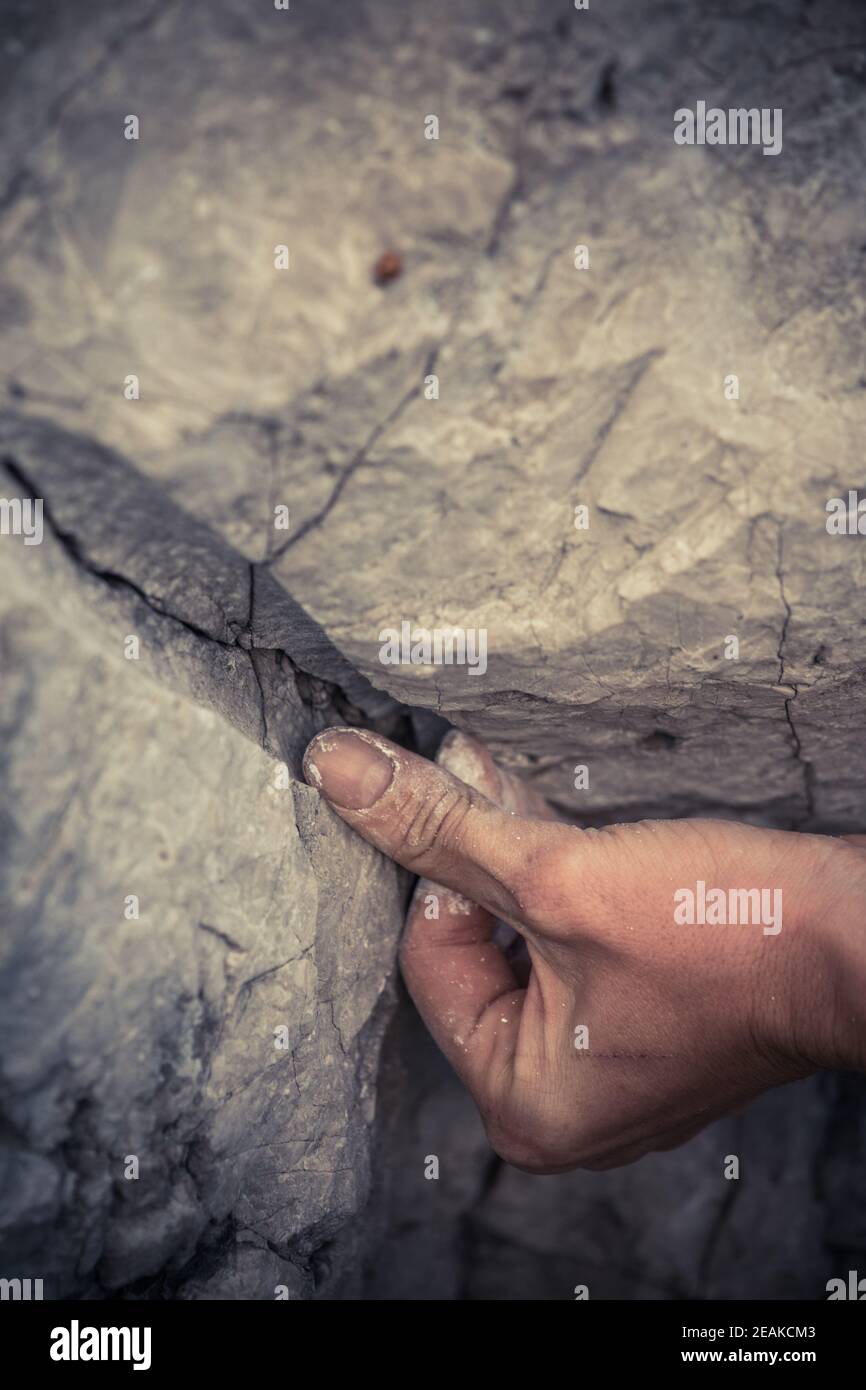 Uomo adulto che tiene a mano su una roccia Foto Stock