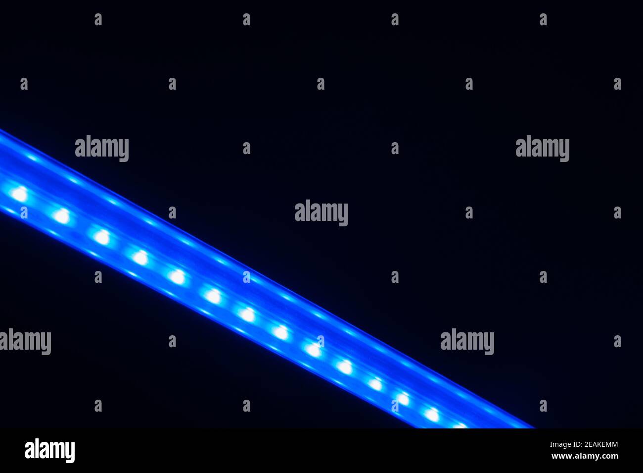 Linea di luci blu diagonali astratte al buio. Foto Stock