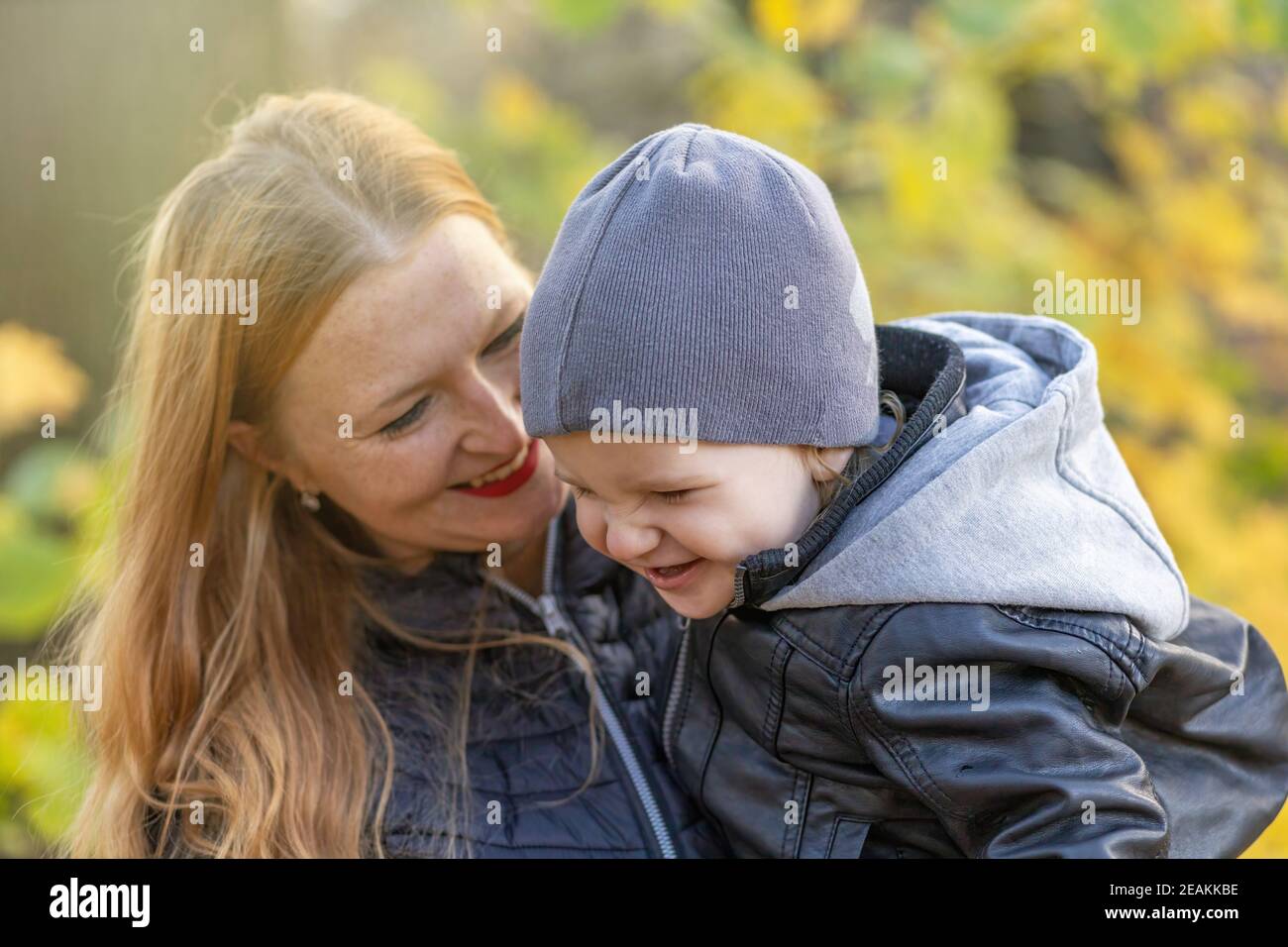 Ridendo la madre dai capelli lunghi e suo figlio stanno posando la natura di autunno di uin. Foto Stock