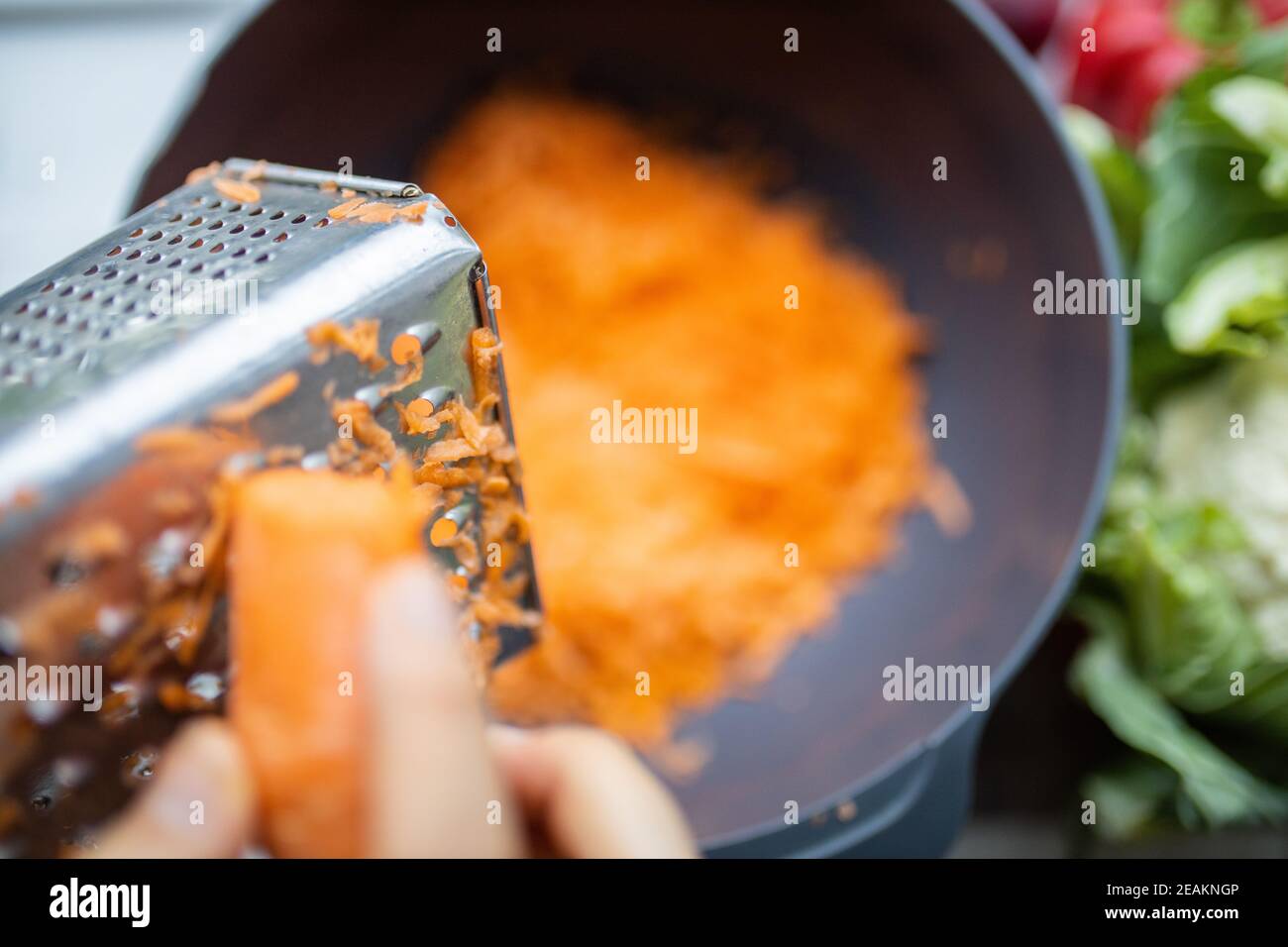 La donna grattugia le carote fresche per cucinare insalata o per