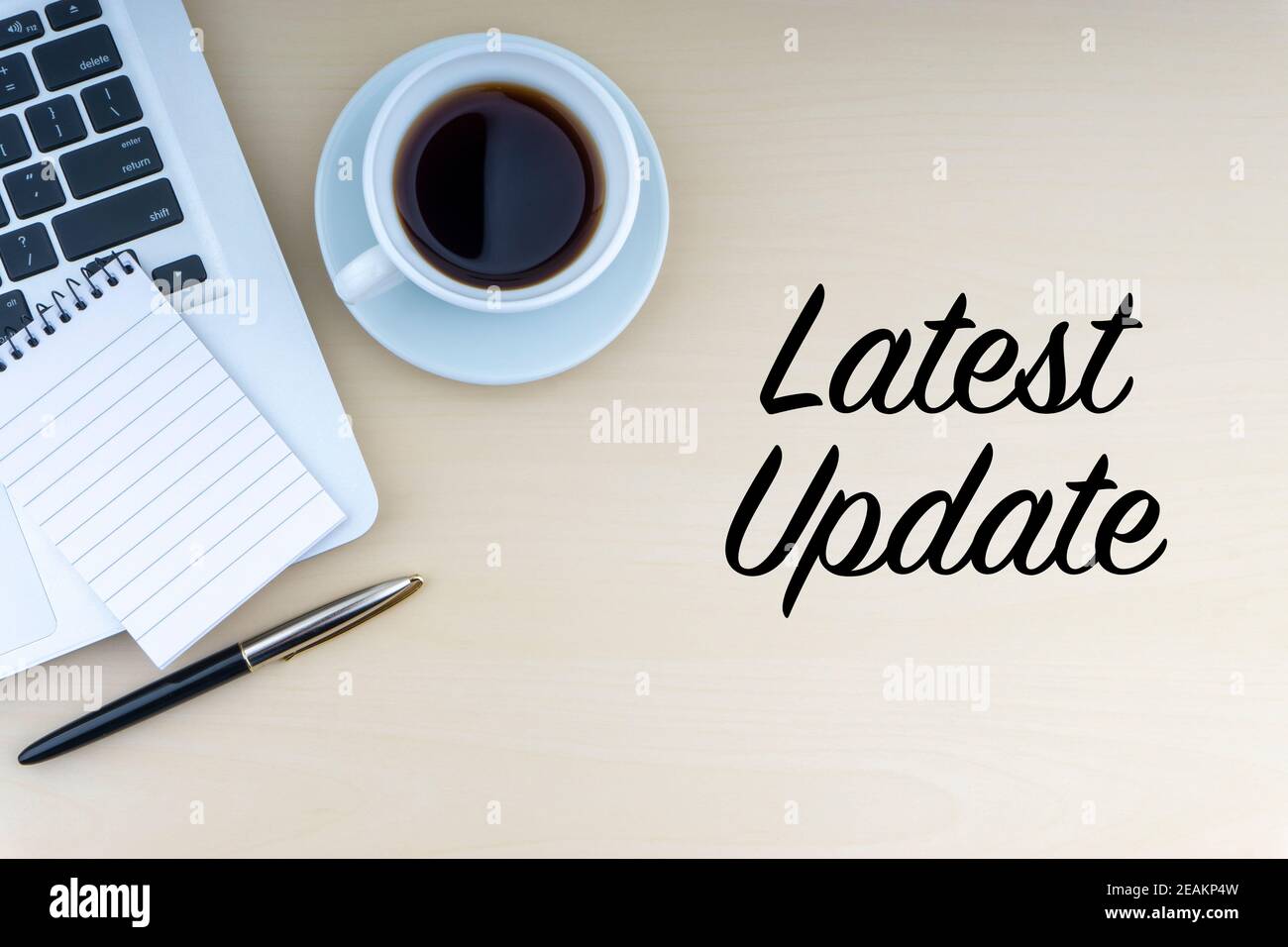 ULTIMO AGGIORNAMENTO testo con penna stilografica, blocco note, computer portatile e tazza di caffè su sfondo di legno Foto Stock