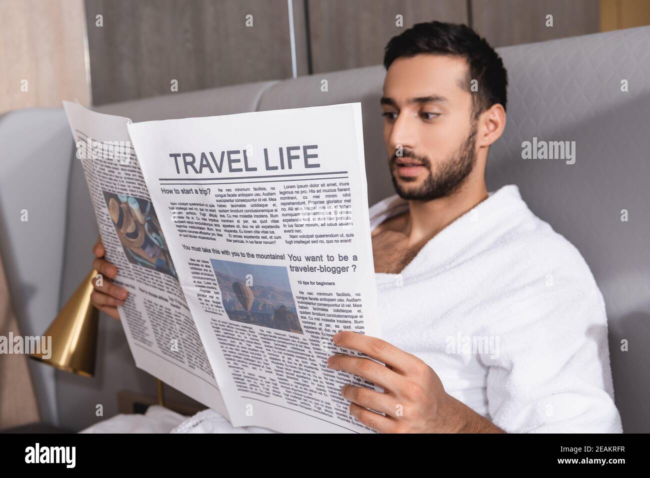 Viaggio vita scritta su giornale in mani di uomo arabo in accappatoio in hotel Foto Stock