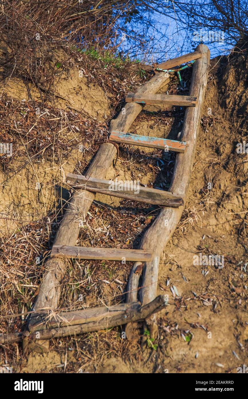 Una scala in legno realizzata localmente in tronchi giace su una scogliera sterrata e si allunga verso il cielo blu. Primo piano Foto Stock
