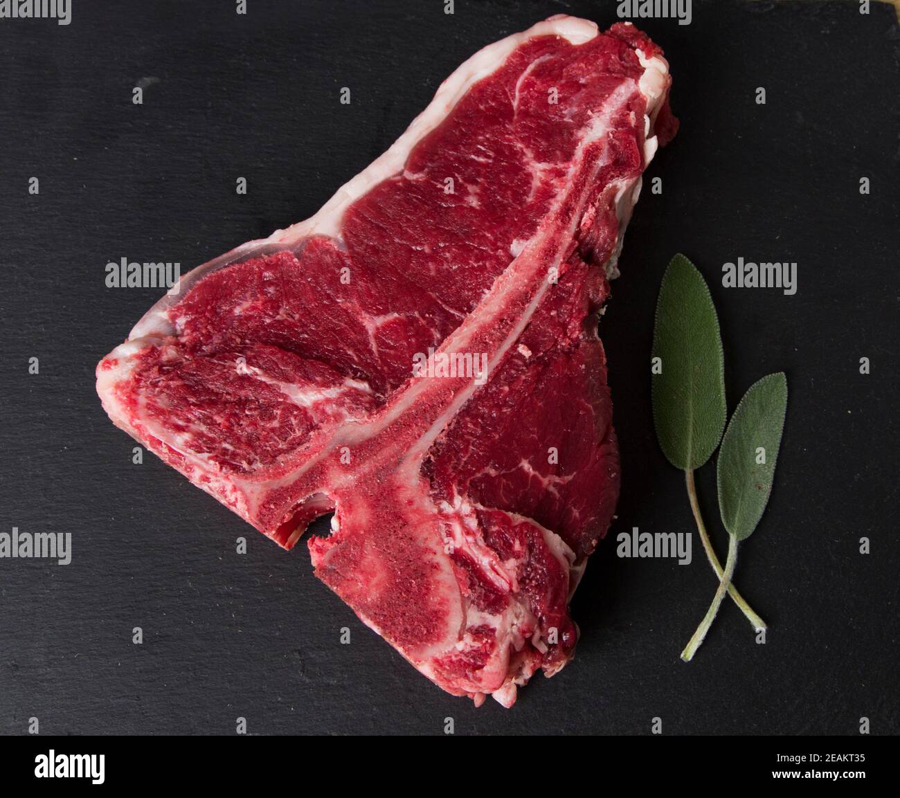 carne cruda fotografata su un tagliere di legno con un sfondo nero Foto Stock