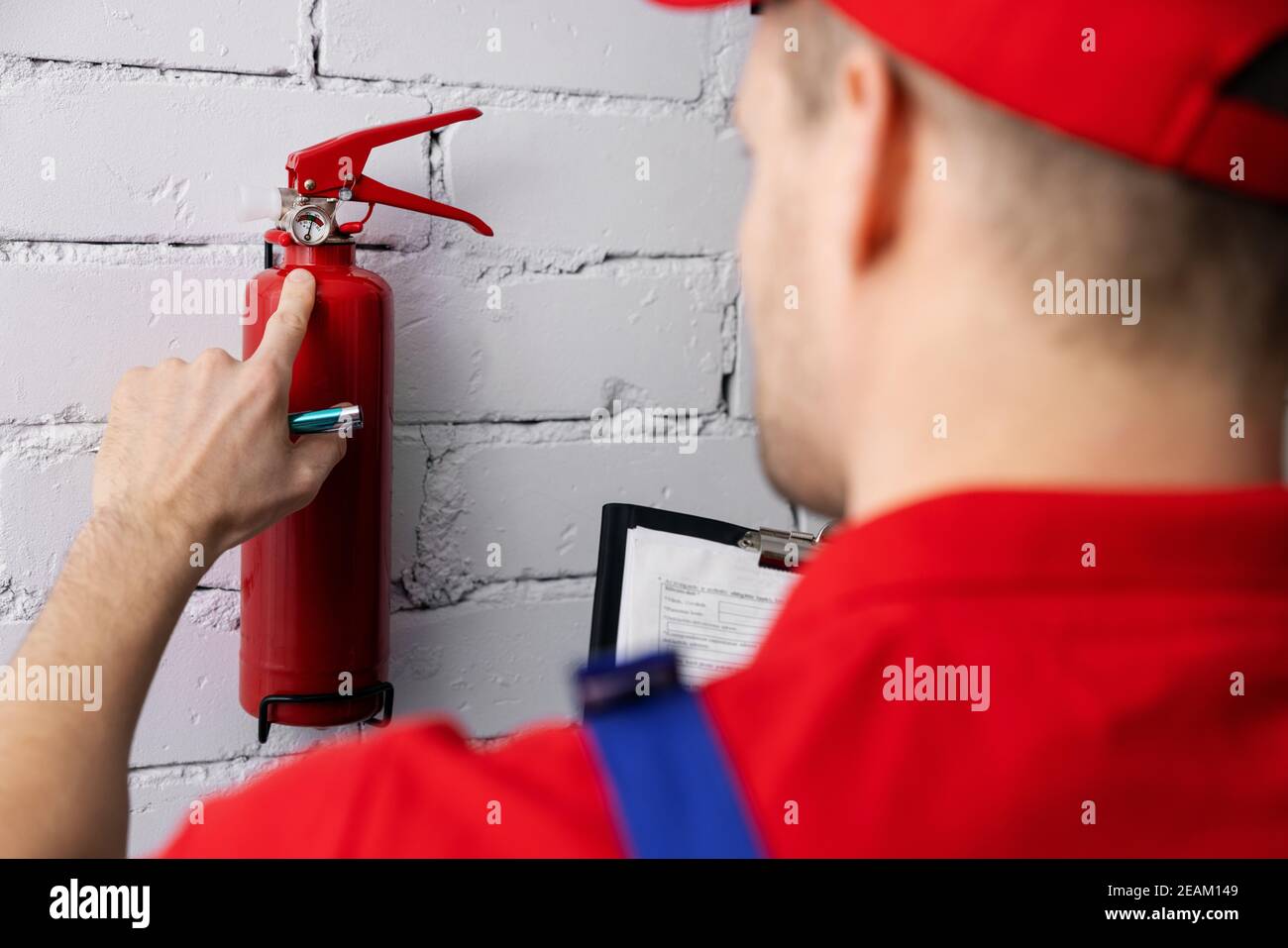 prevenzione e sicurezza antincendio - addetto alla manutenzione che controlla la pressione dell'estintore Foto Stock