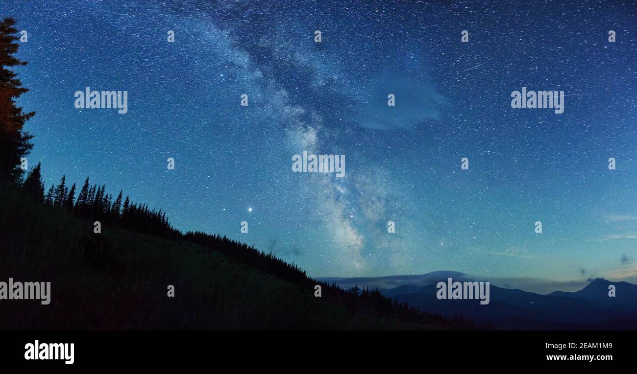 Vista panoramica del paesaggio notturno con la colorata galassia della Via Lattea e molte stelle luminose. Cielo stellato con colline in estate. Bell'universo. Foto Stock