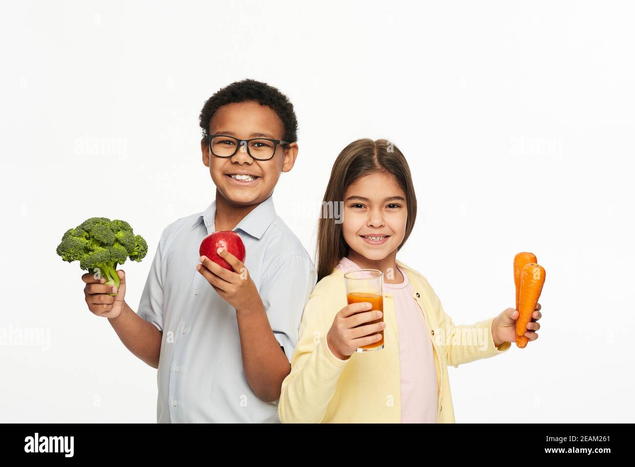 Gruppo multietnico di bambini con verdure sane, frutta e succo di carota. Pubblicità bambini nutrizione sana Foto Stock