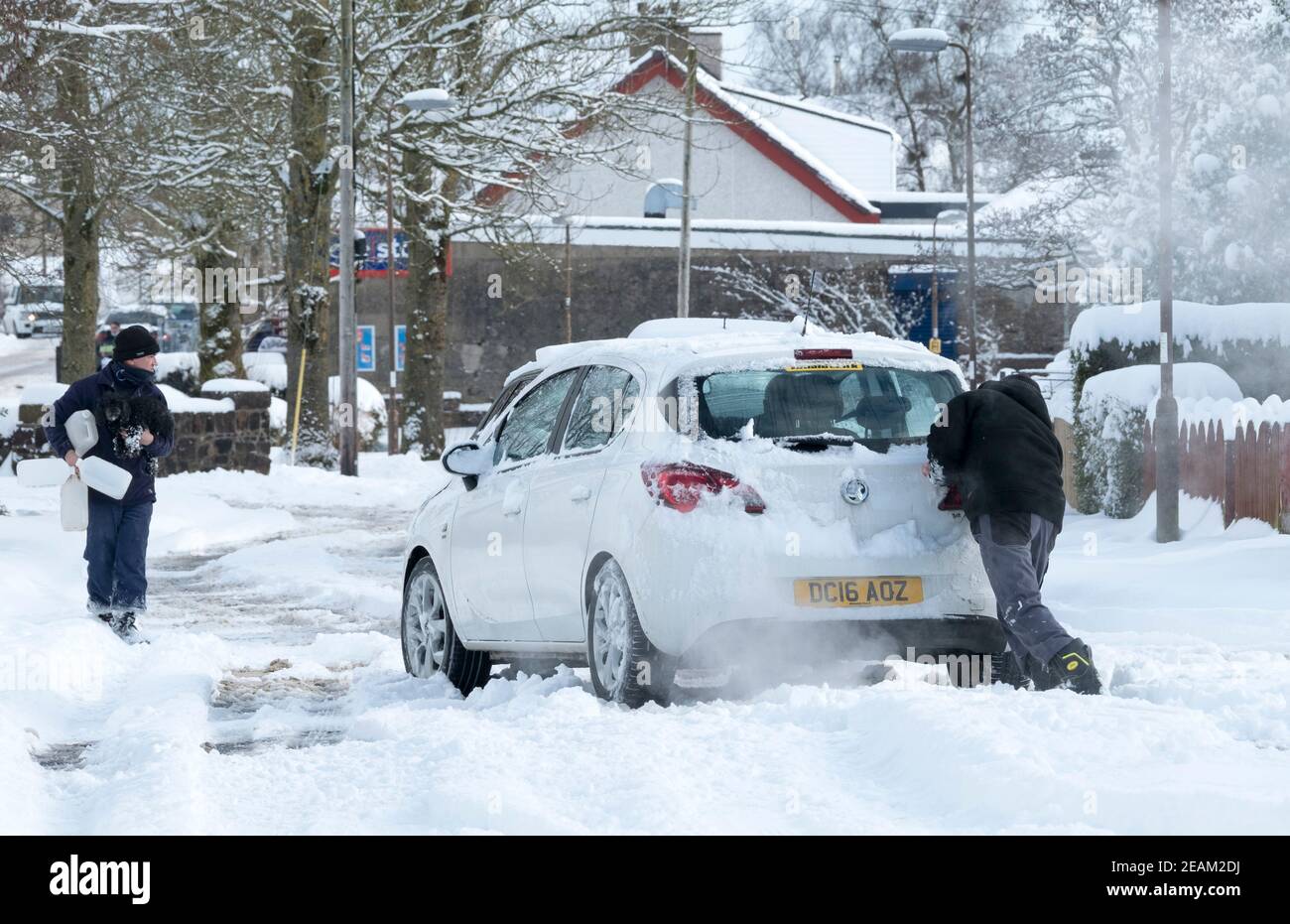 Lothian occidentale, Scozia. Meteo: 10 febbraio 2021 Storm Darcy: Un uomo aiuta a spingere una macchina bloccata nella neve a Stoneyburn, West Lothian, Scozia, Regno Unito. . Credit: Ian Rutherford/Alamy Live News. Foto Stock