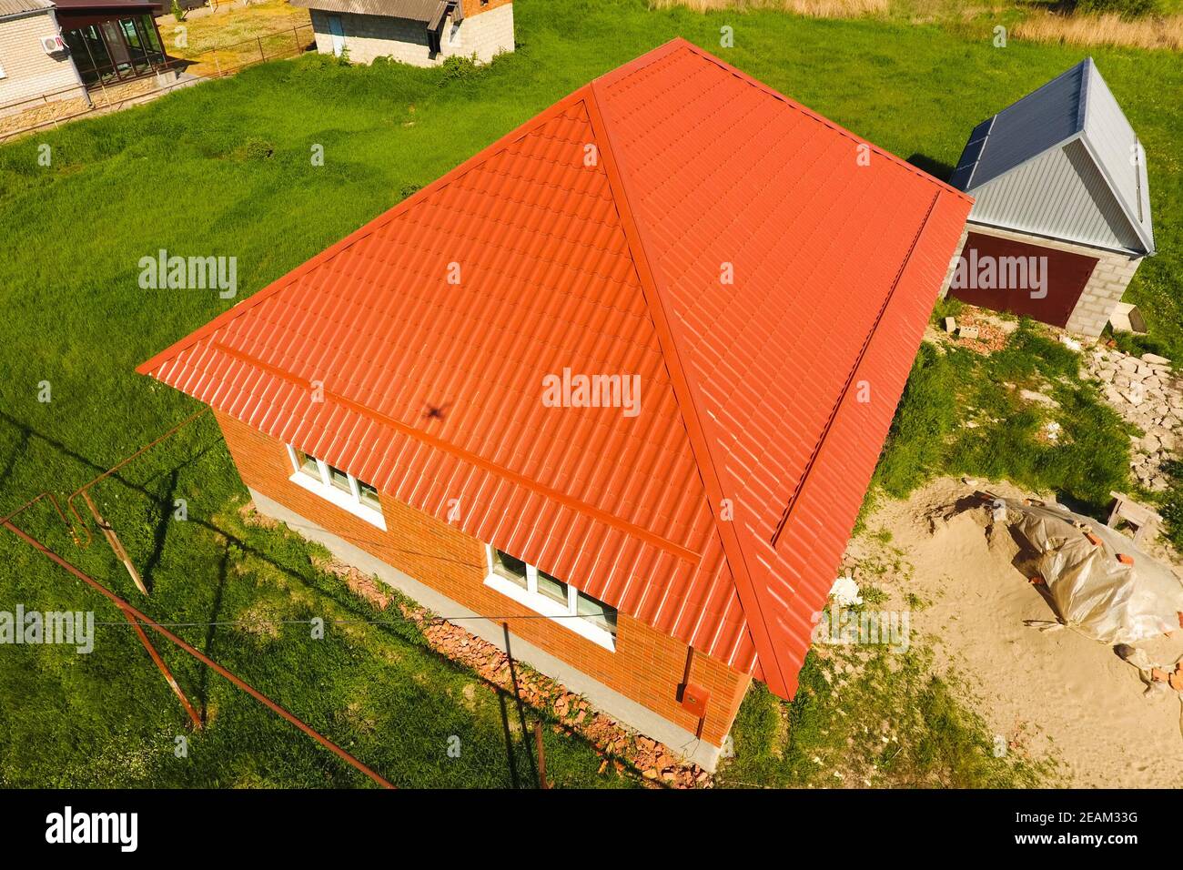 Casa con un tetto arancione di metallo, vista dall'alto. Profilo metallico dipinto corrugato sul tetto. Foto Stock