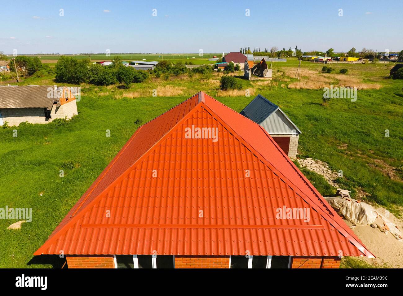 Casa con un tetto arancione di metallo, vista dall'alto. Profilo metallico dipinto corrugato sul tetto. Foto Stock