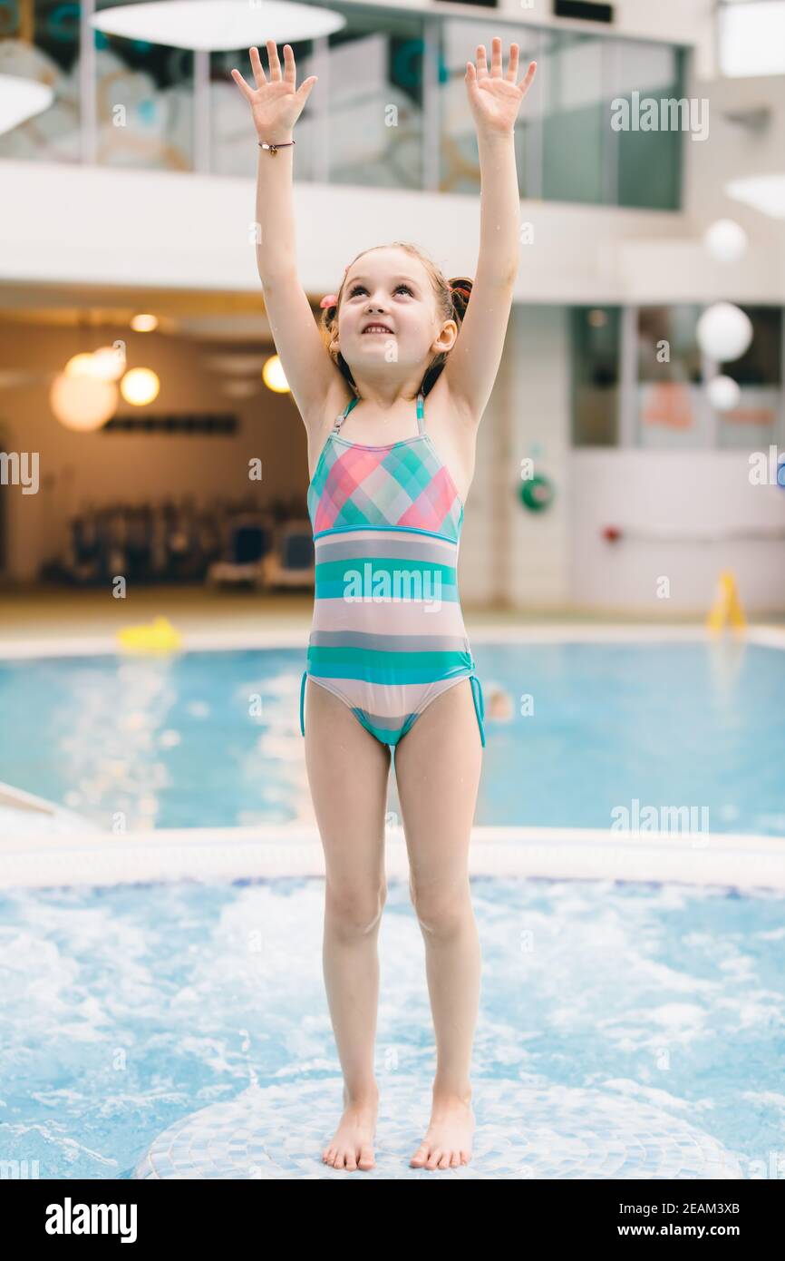 Bambina in piedi sul pavimento, che si alza con le mani. Aquapark. Foto Stock