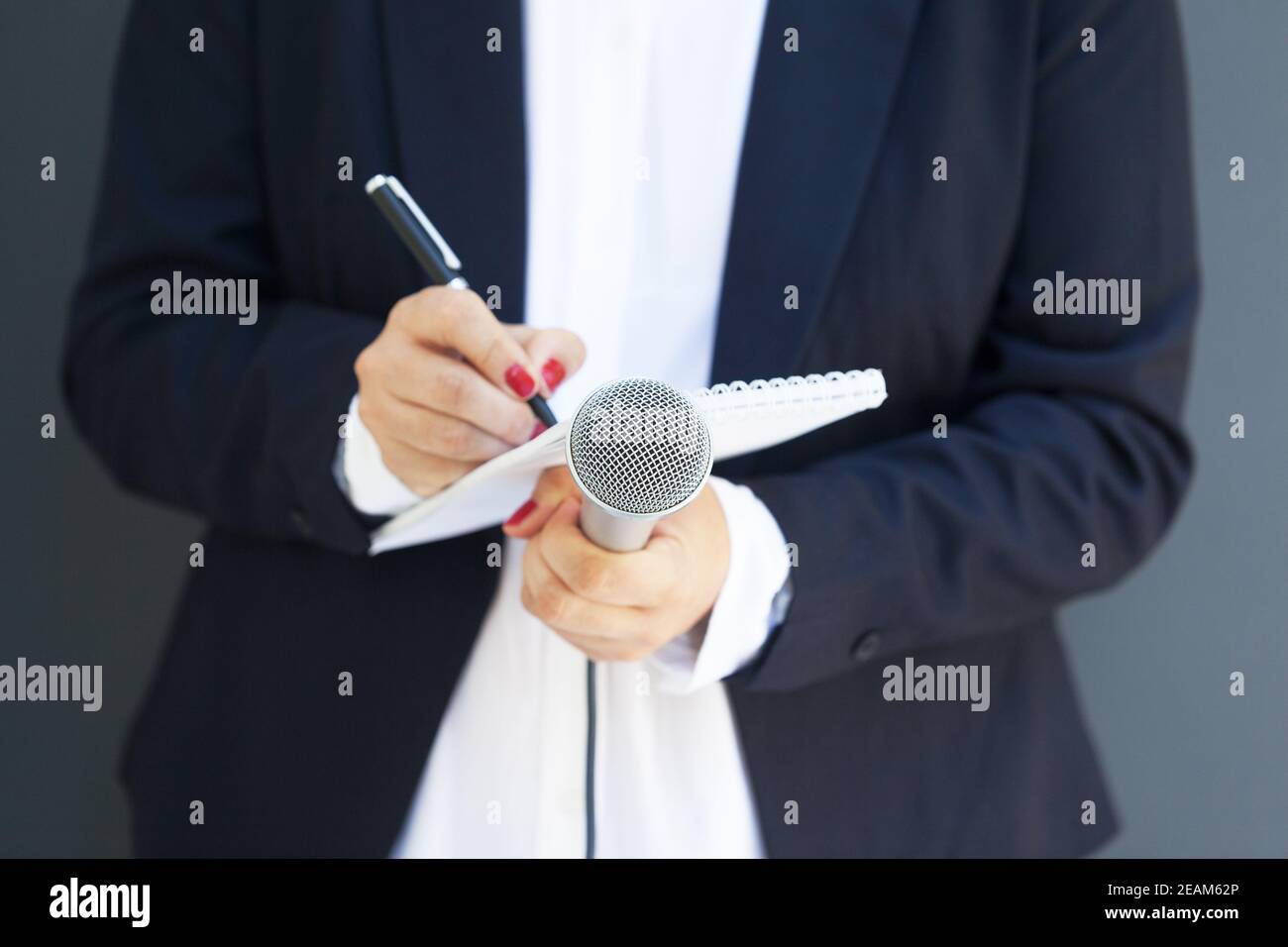 Giornalista femminile alla conferenza stampa o evento mediatico, scrittura di note, microfono Foto Stock