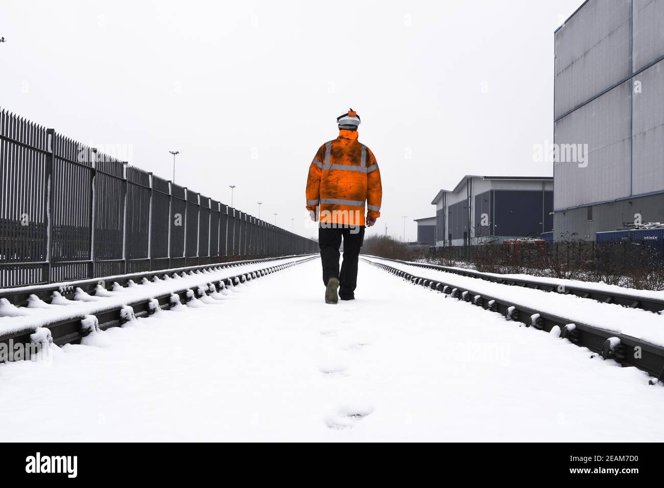 Vista posteriore di una guardia di sicurezza del lavoratore ferroviario che ispeziona il ferrovia durante la neve invernale pesante Foto Stock