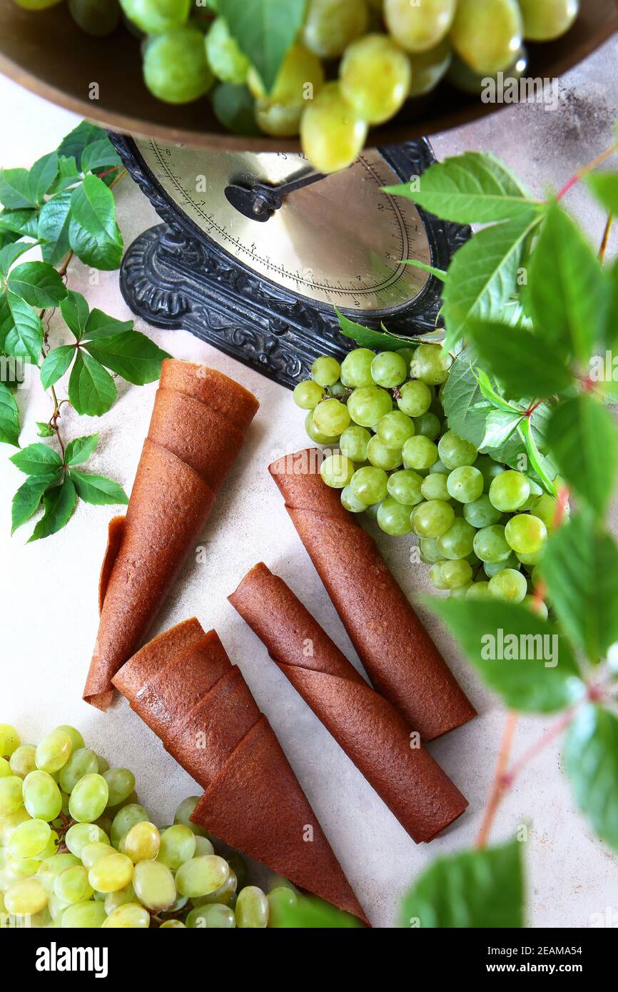 Uve leggere e vintage. Pastilla dalle uve. Prodotto naturale senza conservanti. Cibo per vegetariani. Grappoli di uva su sfondo chiaro. Foto verticale. Foto Stock