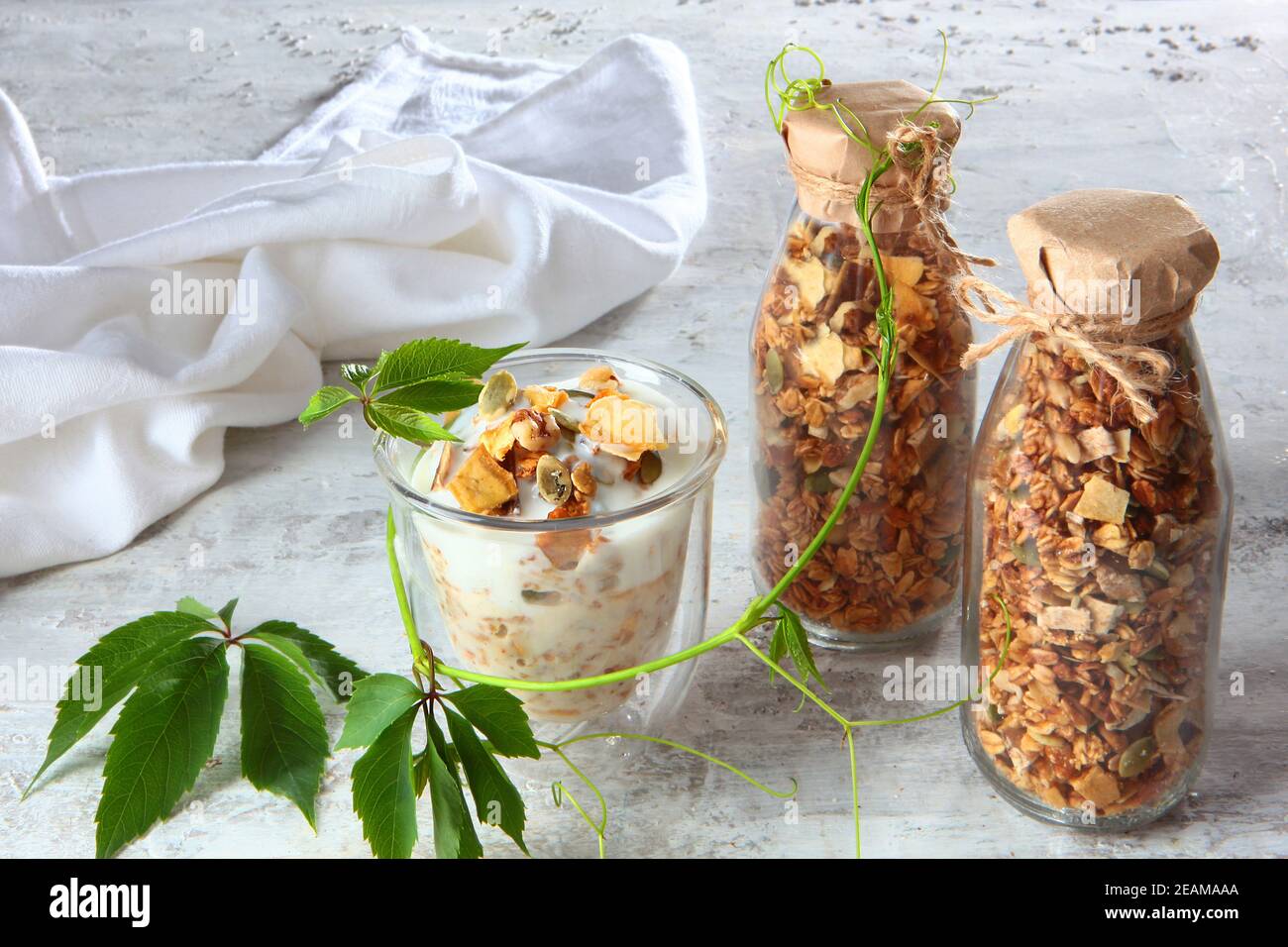 Muesli con yogurt in un bicchiere trasparente su sfondo chiaro. Granola in bottiglia di vetro. Cibo sano a basso contenuto calorico. Prodotto naturale. Cibo vegetariano. Foto Stock