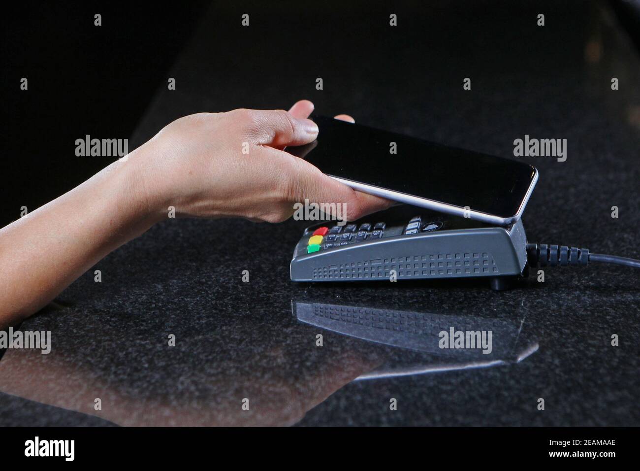 Pagamento tramite telefono cellulare. Pagamento tramite telefono cellulare attraverso il terminale nel ristorante, negozio. Primo piano della mano delle donne con il telefono cellulare al momento del pagamento dell'acquisto. Foto Stock