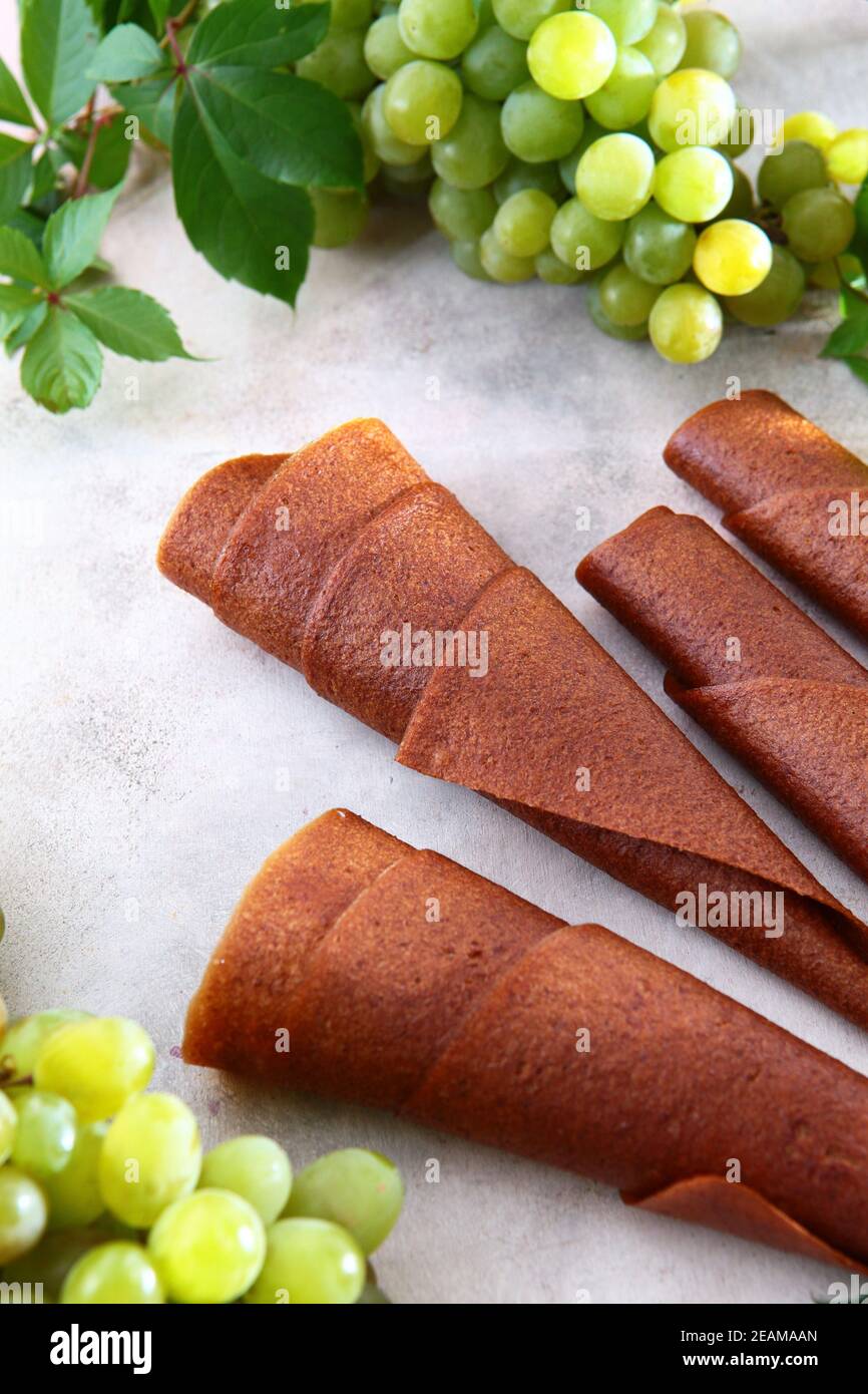 Il marshmallow di uva naturale chiaro viene arrotolato in un tubo. Bioprodotto naturale senza conservanti. Cibo per vegetariani. Foto su sfondo chiaro. Vista dall'alto. Foto Stock