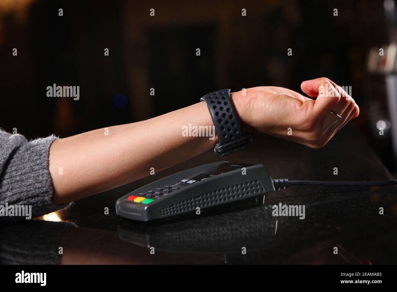 Pagamento per gli orari di acquisto attraverso il terminal nel ristorante, negozio. Mano da donna primo piano con un orologio quando si paga per l'acquisto. Foto Stock
