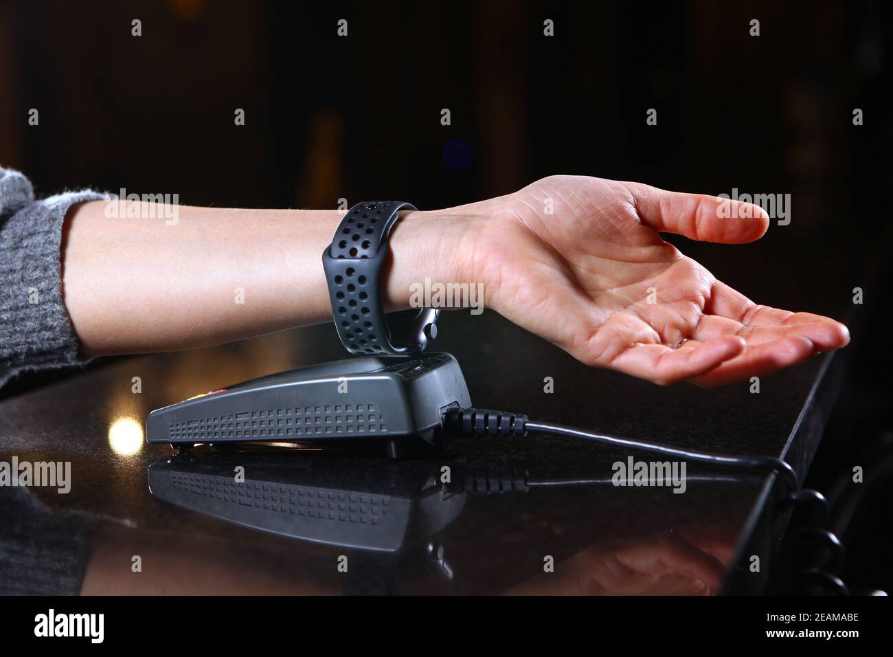 Pagamento per gli orari di acquisto attraverso il terminal nel ristorante, negozio. Mano da donna primo piano con un orologio quando si paga per l'acquisto. Foto Stock