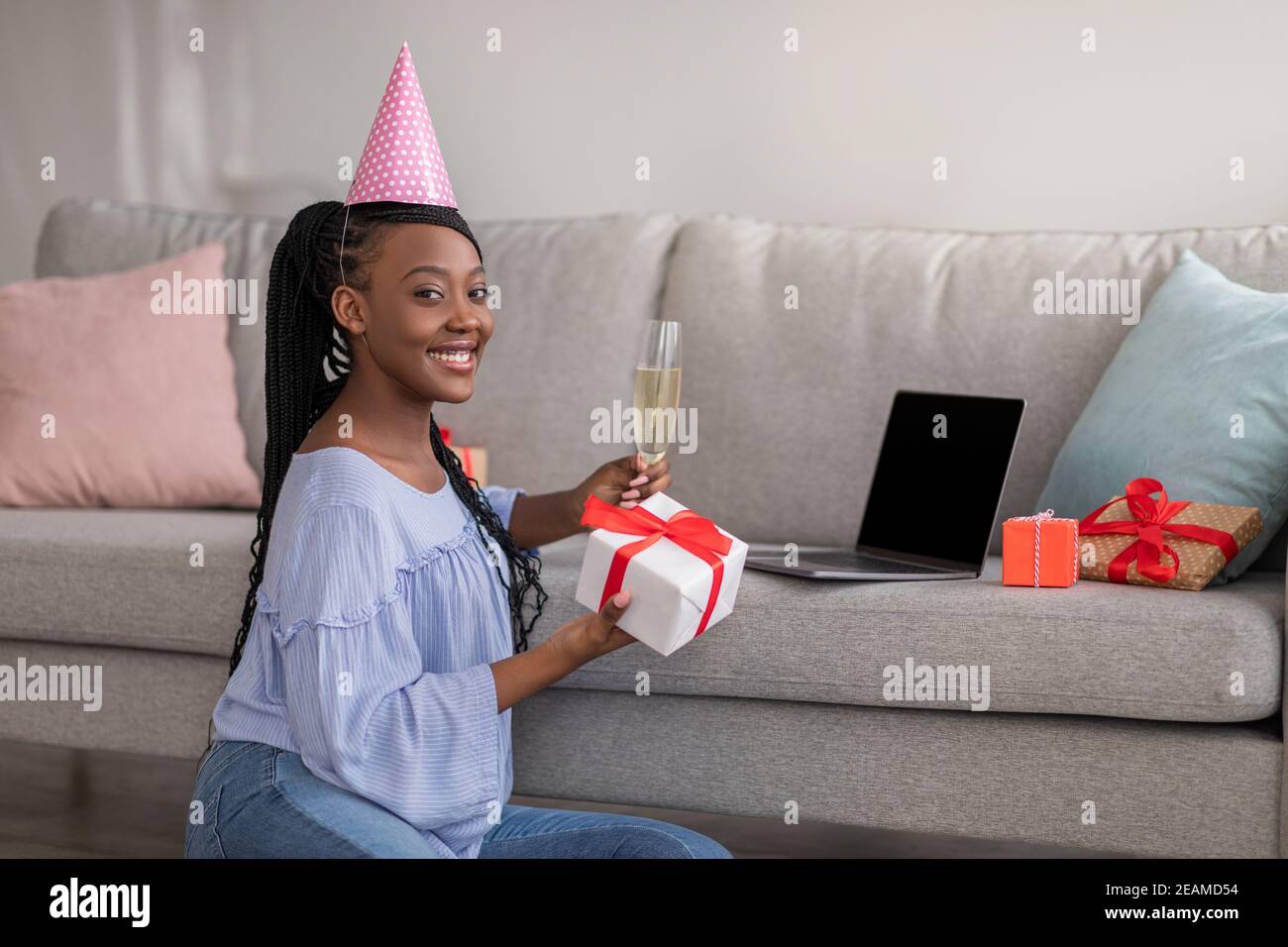 Bella donna nera con champagne e presente usign laptop Foto Stock