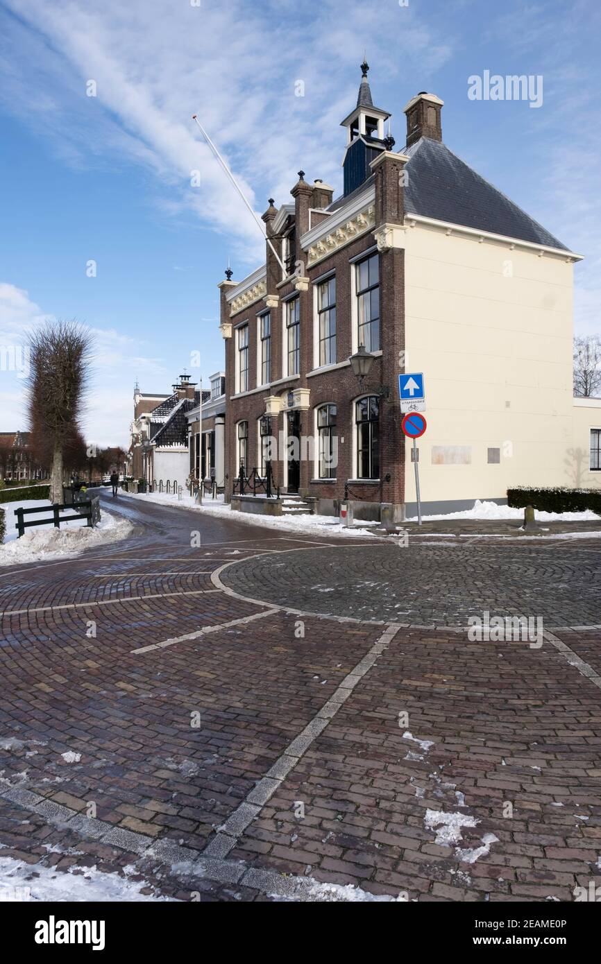 Ex municipio nel centro della città di IJlst, Frisia nella neve con cielo blu Foto Stock
