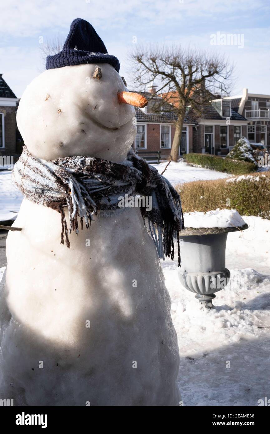 Snowman in un giardino nella città IJlst in Friesland, Paesi Bassi con cielo blu e sole Foto Stock